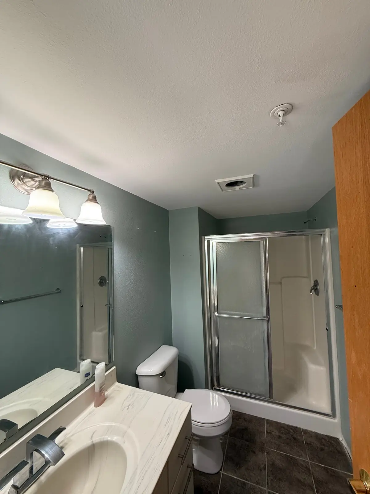 Finished bathroom with smooth ceiling and soft green painted walls