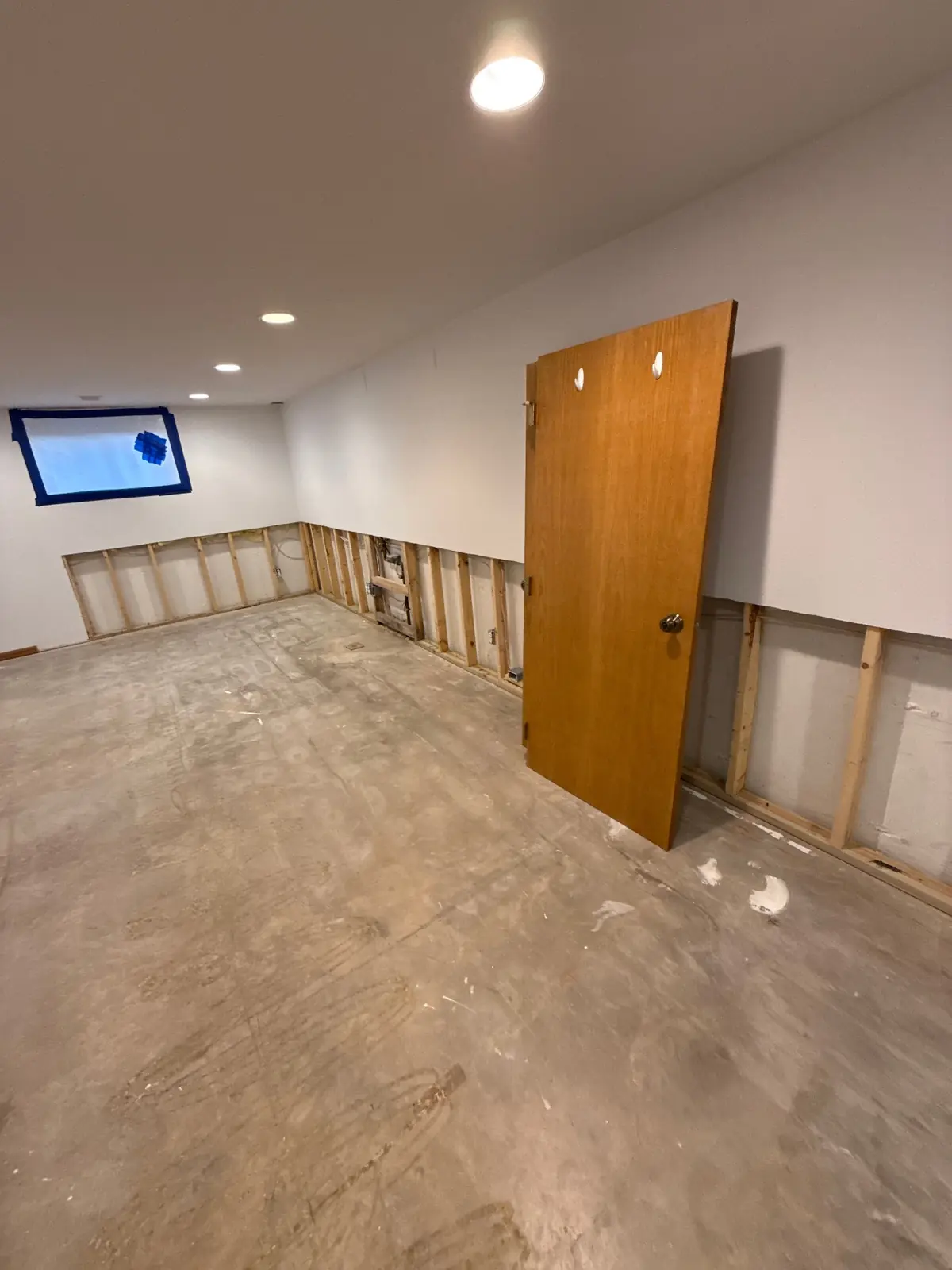 Basement with lower drywall removed exposing studs