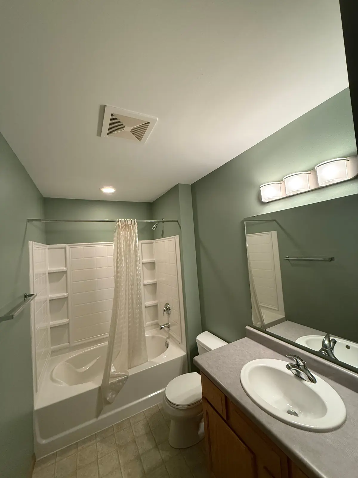 Bathroom painted a soft sage green with a crisp white ceiling