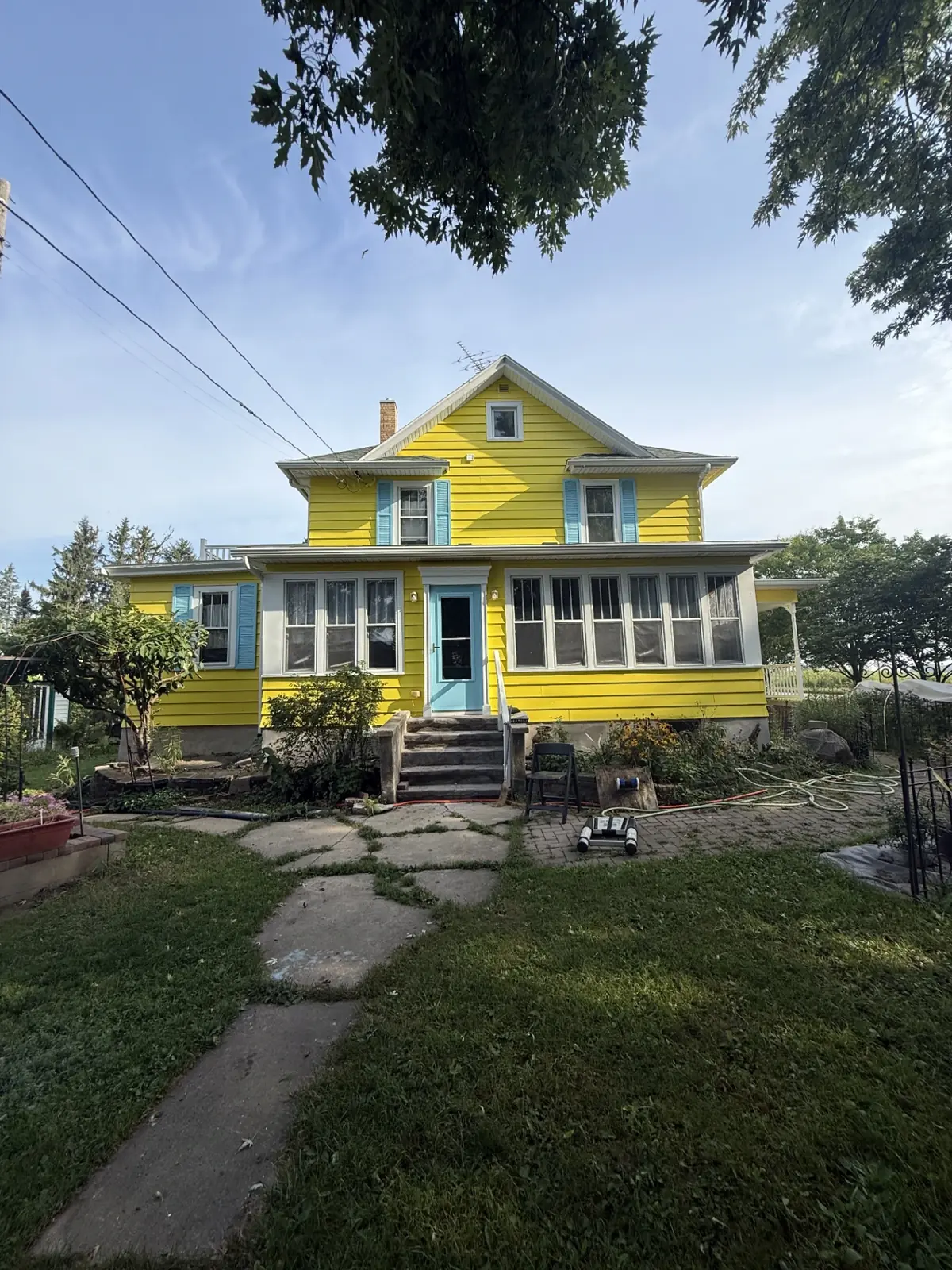 Farmhouse front repainted bright yellow with fresh white and teal trim