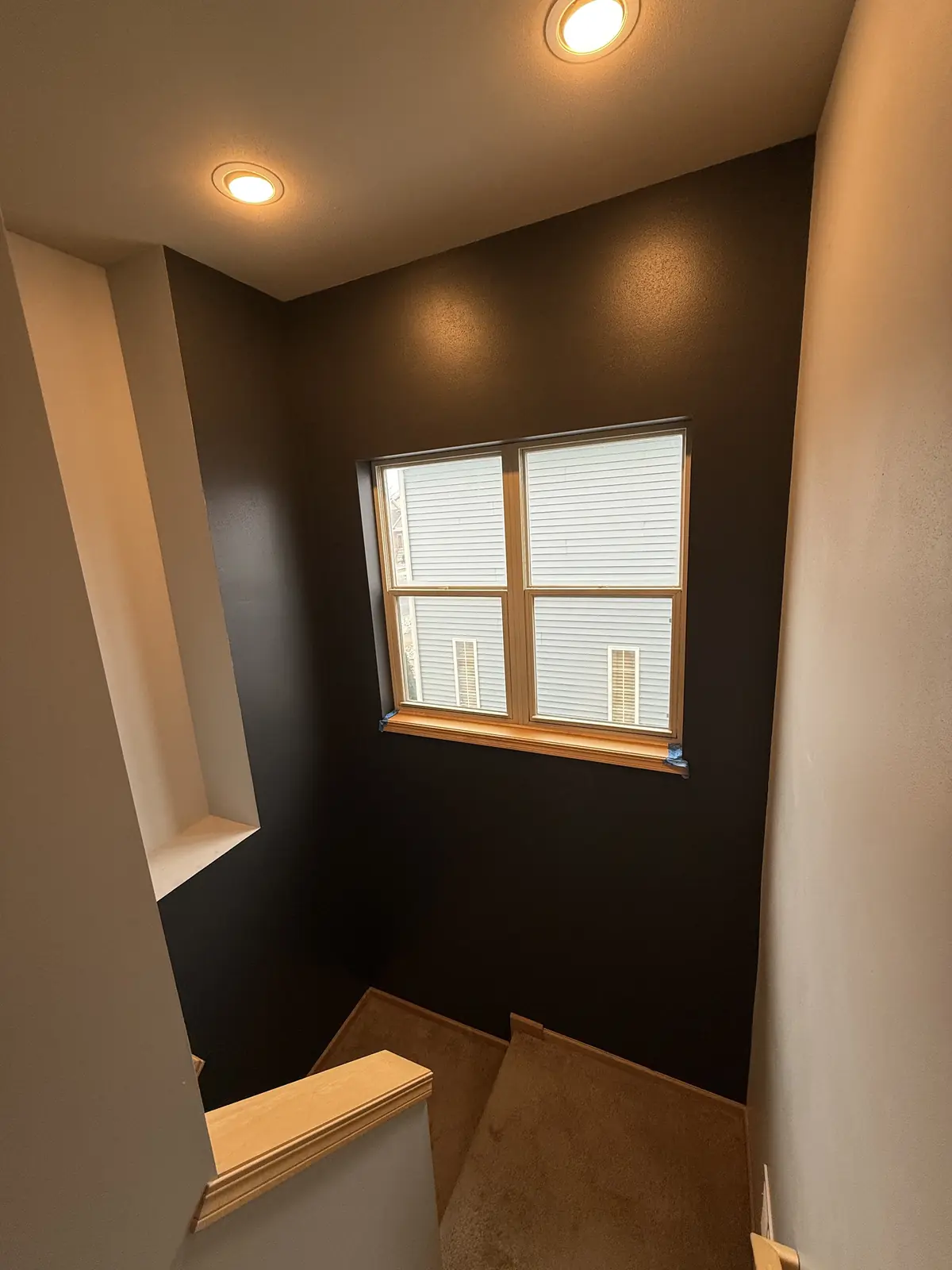 Dark accent wall painted in a stairwell with crisp edges and warm trim