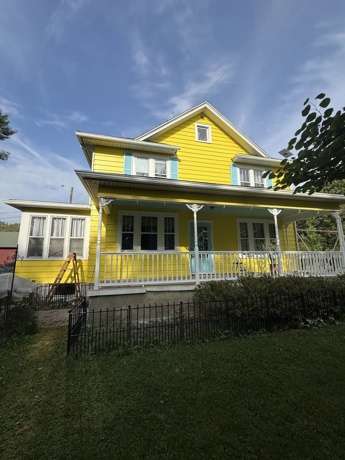 Repainted farmhouse porch with bright yellow siding and white railings