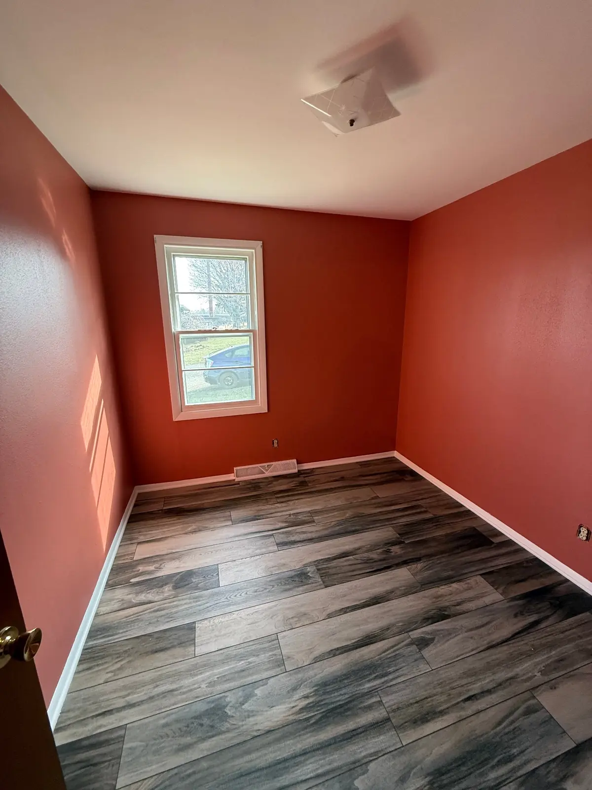Empty bedroom painted a warm terracotta with crisp white trim