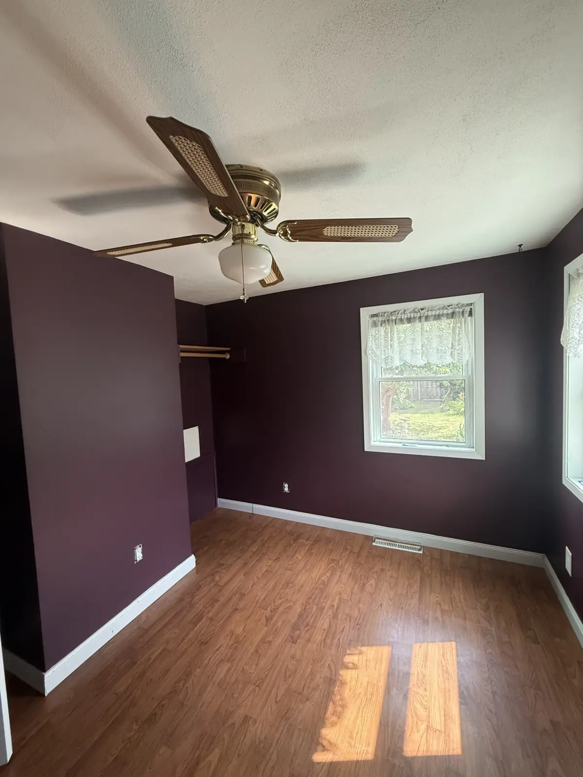Empty bedroom painted deep plum with white trim