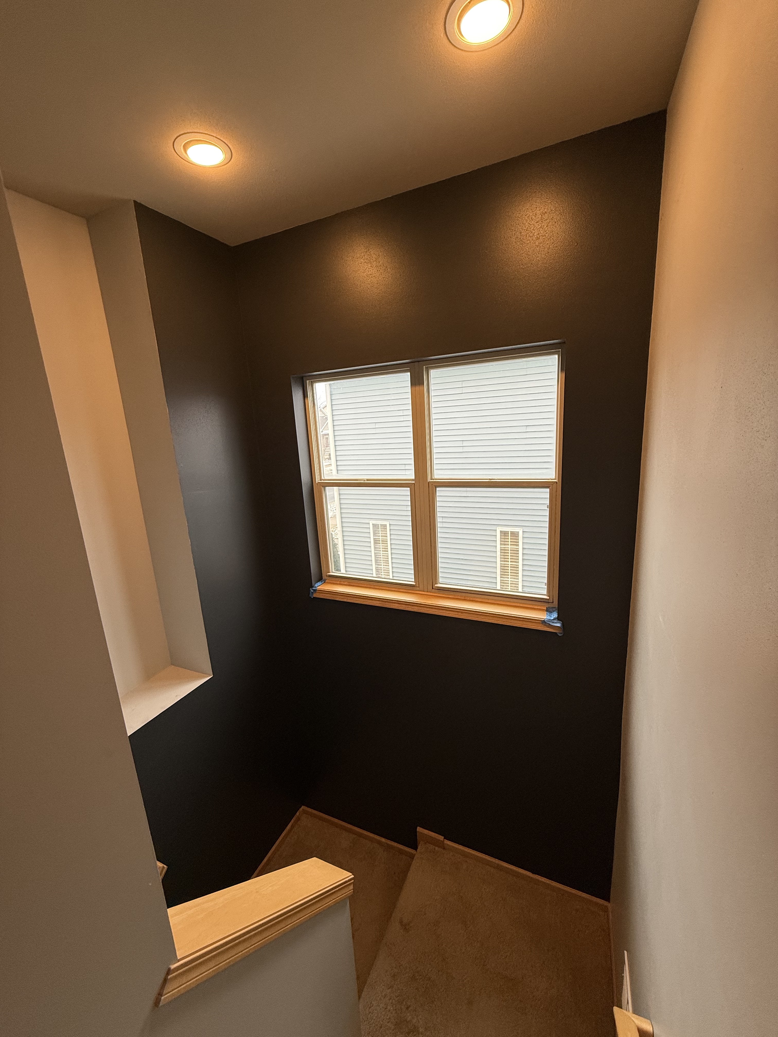 Dark accent wall painted in a stairwell with crisp edges and warm trim